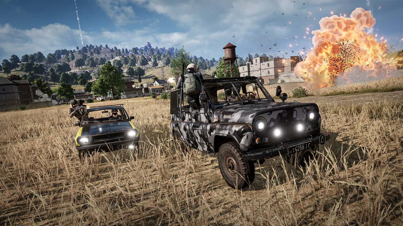 A camouflaged jeep driving through a wheat field with an explosion behind it in PUBG: Battlegrounds